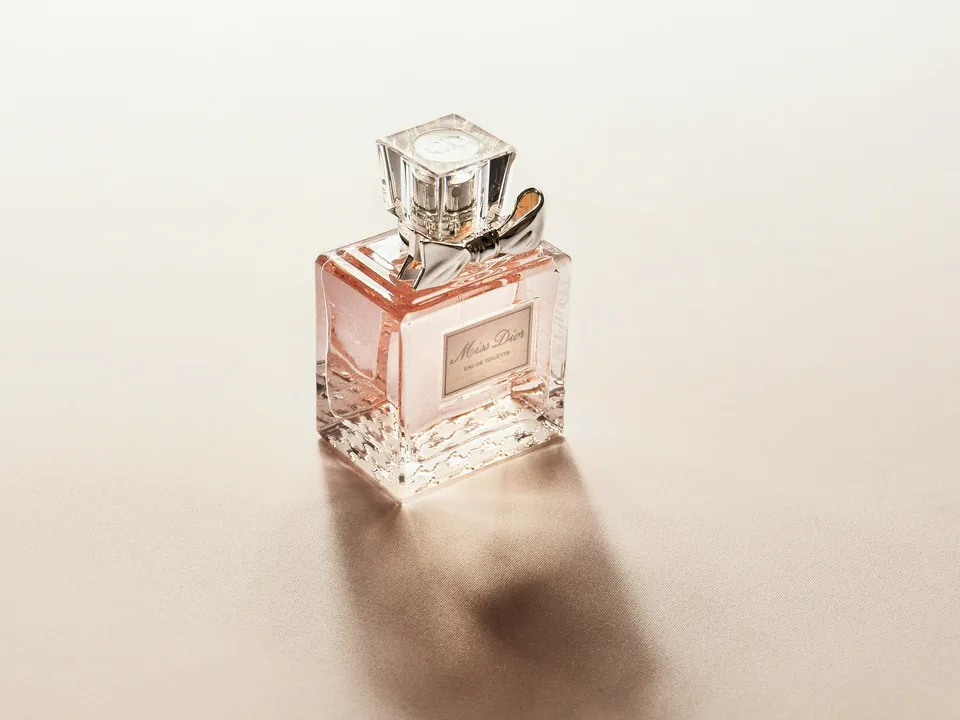 A pink perfume bottle on a pale backdrop
